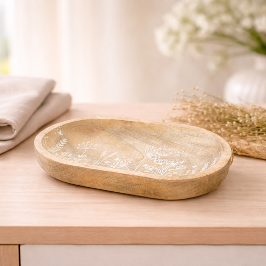 Wooden tray with white floral patterns on a wooden surface with a blurred background