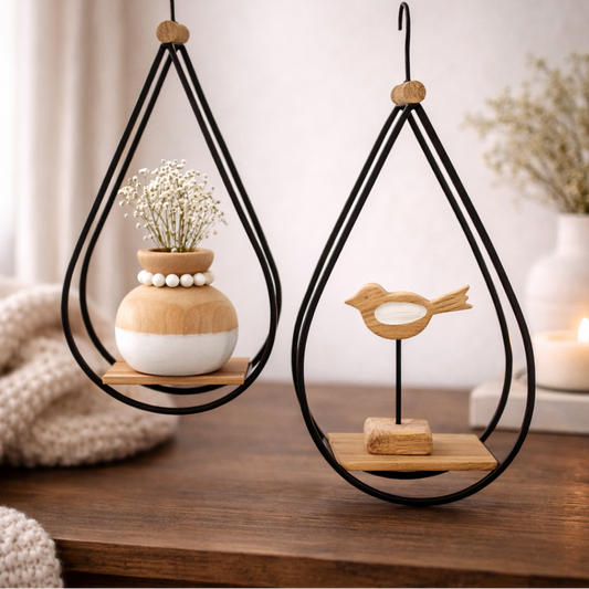 Decorative hanging shelves with plants and a bird figurine on a wooden surface.